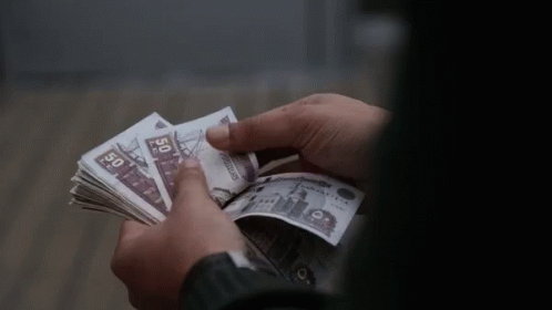 a person holding a stack of 50 dollar bills