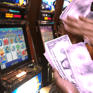 A Person Holding A Stack Of Money In Front Of A Slot Machine With The Number 10 On The Screen GIF