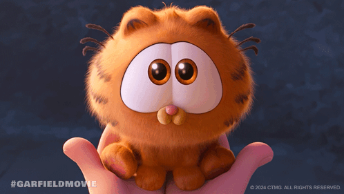A Person Holding A Stuffed Garfield Cat With A Nut In Its Mouth GIF