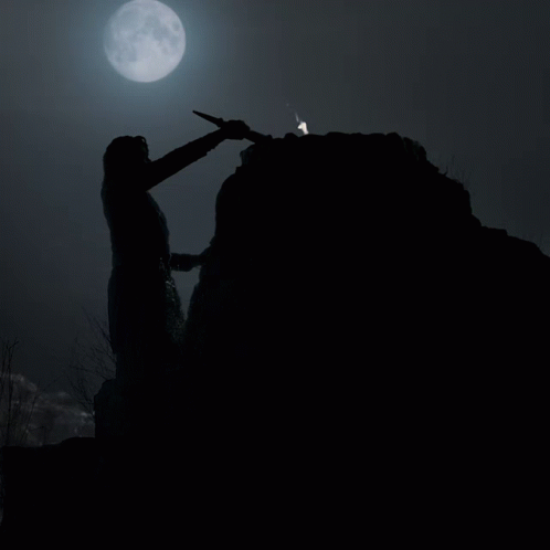 A Person Holding A Torch On Top Of A Rocky Hill With A Full Moon In The Background GIF