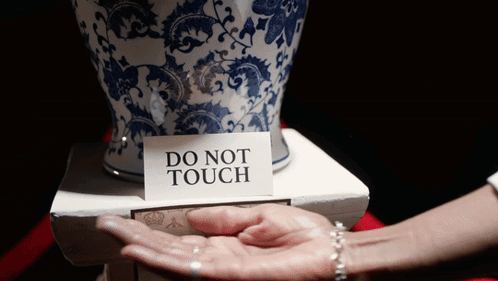 A Person Holding A Vase With A Do Not Touch Sign On It GIF