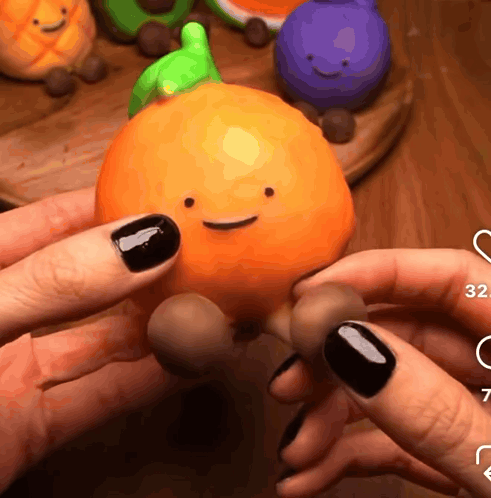 A Person Holding An Orange With A Face On It GIF
