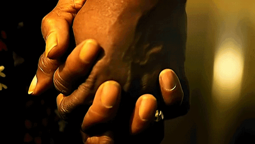 A Person Holding Another Person 'S Hand In A Dark Room GIF