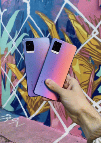 A Person Holding Two Vivo Phones In Front Of A Colorful Mural GIF