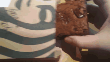 A Person Holds A Brownie In Front Of A Starbucks Logo GIF