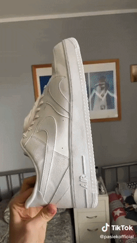 A Person Holds A Pair Of White Nike Air Force 1 Sneakers GIF