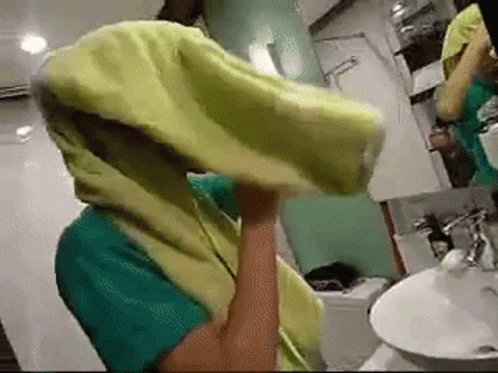 A Person In A Bathroom With A Yellow Towel On Their Head GIF