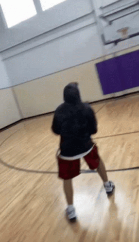 A Person In A Black Hoodie And Red Shorts Is Playing Basketball On A Court GIF