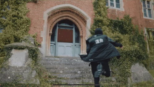 A Person In A Black Jacket With Chinese Writing On The Back Is Running Down Stairs GIF