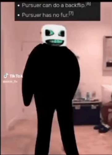 A Person In A Black Suit With A White Mask On Their Face . GIF