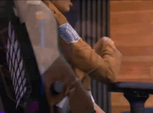 A Person In A Brown Jacket Is Sitting In A Chair With Their Arms Crossed . GIF