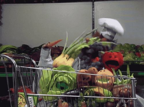A Person In A Chef 'S Hat Pushes A Shopping Cart Full Of Vegetables GIF