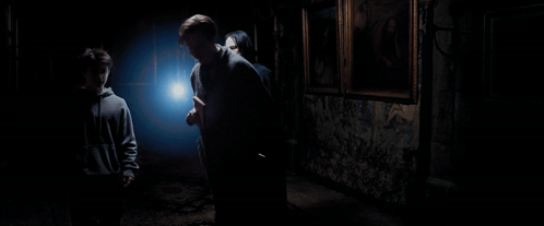 A Person In A Dark Room Holding A Light In Their Hand GIF
