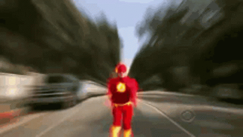 A Person In A Flash Costume Is Walking Down A Street . GIF