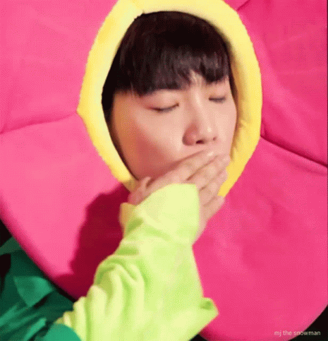 A Person In A Flower Costume Is Covering Their Mouth With Their Hand . GIF
