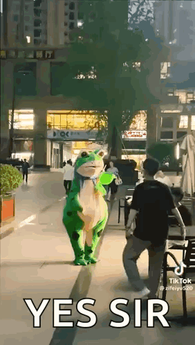 A Person In A Frog Costume Is Walking Down A Street . GIF