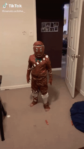 A Person In A Gingerbread Man Costume Is Standing In A Room With A Door Open GIF