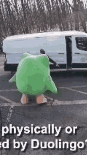 A Person In A Green Frog Costume Is Standing In Front Of A Van . GIF