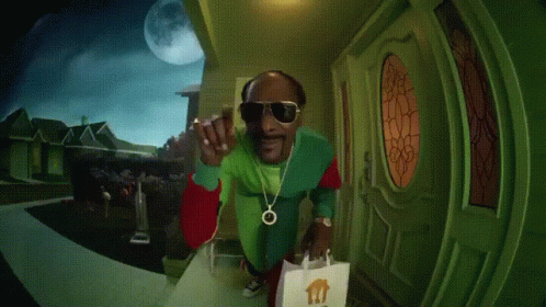 A Person In A Green Jacket Is Standing In Front Of A Door With A Bag In Front Of It GIF