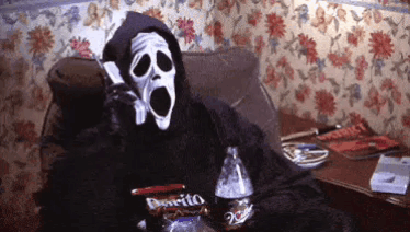 A Person In A Grim Reaper Costume Is Sitting On A Couch Talking On A Cell Phone GIF