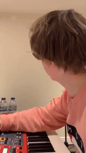 A Person In A Pink Shirt With The Letter M On It Is Playing A Keyboard GIF