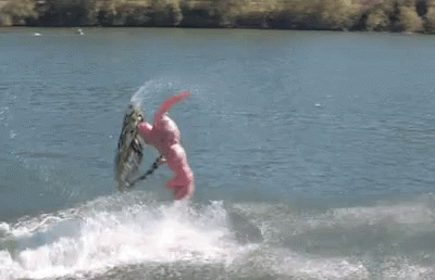 A Person In A Pink Suit Is Riding A Wave On A Surfboard GIF