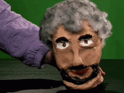 A Person In A Purple Jacket Is Holding A Puppet Head GIF