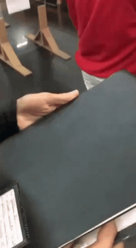A Person In A Red Shirt Is Holding A Black Book In Their Hands . GIF