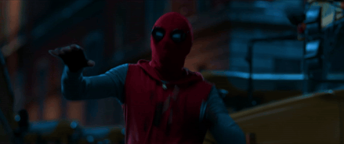 A Person In A Red Spiderman Costume Is Pointing At Something In The Dark GIF