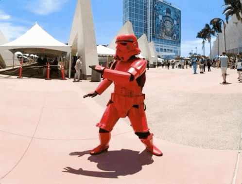 A Person In A Red Storm Trooper Costume Stands In Front Of A Building That Says Disney GIF
