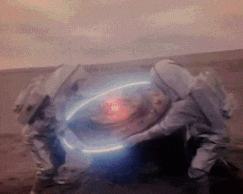 A Person In A Space Suit Is Holding A Glowing Object In Their Hands GIF