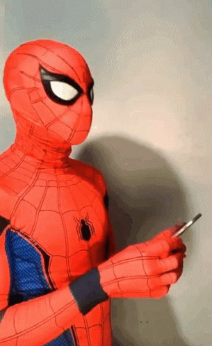 A Person In A Spiderman Costume Is Holding A Cell Phone In Their Hand . GIF