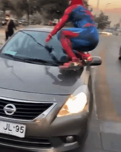 A Person In A Spiderman Costume Is Riding On The Hood Of A Nissan GIF