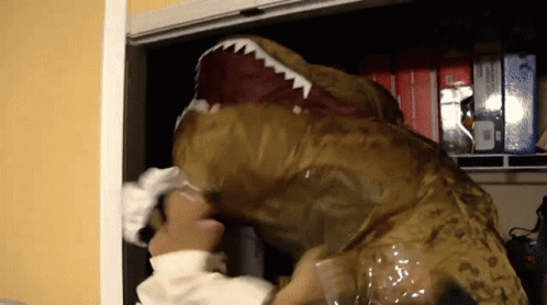 A Person In A T-Rex Costume Reaches Into A Closet Full Of Boxes GIF