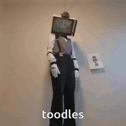 A Person In A Tv Head Costume Holding A Syringe And The Word Noodles Below Them GIF