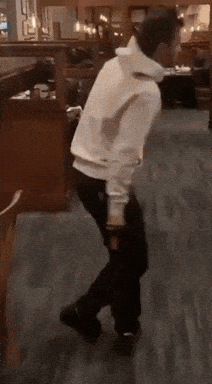 A Person In A White Hoodie Is Dancing In A Restaurant GIF