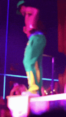 A Person In Green Pants And Yellow Boots Is Standing On A Stage GIF