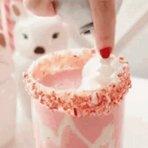 A Person Is Adding Whipped Cream To A Milkshake With Sprinkles . GIF