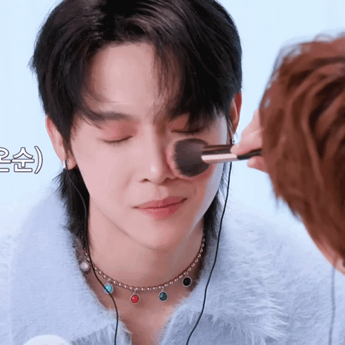 A Person Is Applying Makeup To Another Person 'S Face With A Brush GIF