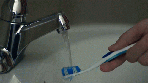 A Person Is Brushing Their Teeth In A Sink With Water Running From The Faucet GIF