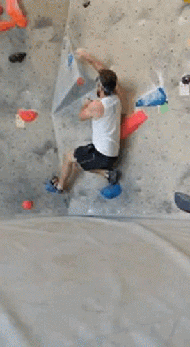 a person is climbing a climbing wall in a gym .