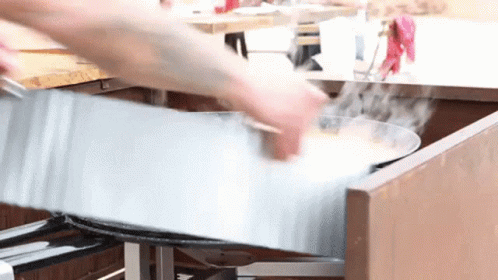A Person Is Cooking Food In A Metal Pan In A Kitchen GIF