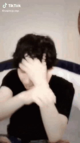 A Person Is Covering Their Face With Their Hand . GIF