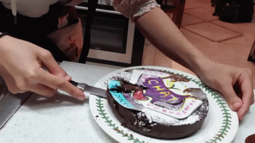 A Person Is Cutting A Chocolate Cake With A Picture Of A Unicorn On It GIF