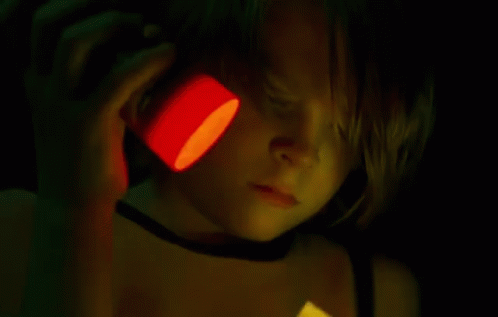 A Person Is Cutting A Piece Of Paper With Scissors In A Dark Room GIF