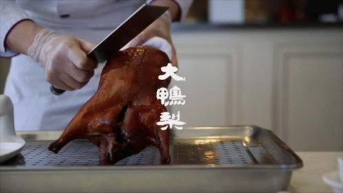 a person is cutting a roasted duck with chinese writing on the bottom