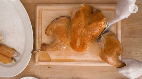 A Person Is Cutting A Turkey On A Cutting Board With The Number 52 On The Bottom Right GIF