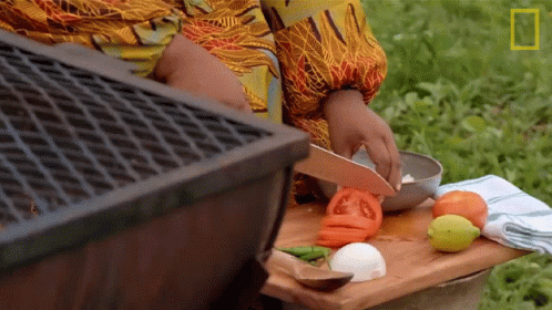 A Person Is Cutting Tomatoes On A Cutting Board Outside GIF