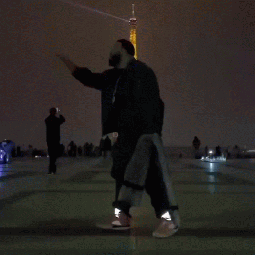 A Person Is Dancing In Front Of The Eiffel Tower At Night GIF