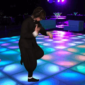 A Person Is Dancing On A Dance Floor With Blue And Purple Lights Behind Them GIF